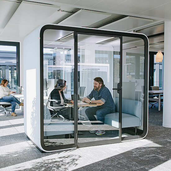 Vorwerk: Foto: Zwei Personen sitzen in einer schalldichten Meeting-Box, die man auch Think Tank, zu deutsch: Denkfabrik nennt, und tauschen sich zu einem Thema aus.